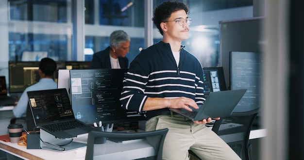 Coding man and thinking with laptop in office for debugging solution software update or app development deadline Night coder or technology for website troubleshooting problem solving or overtime