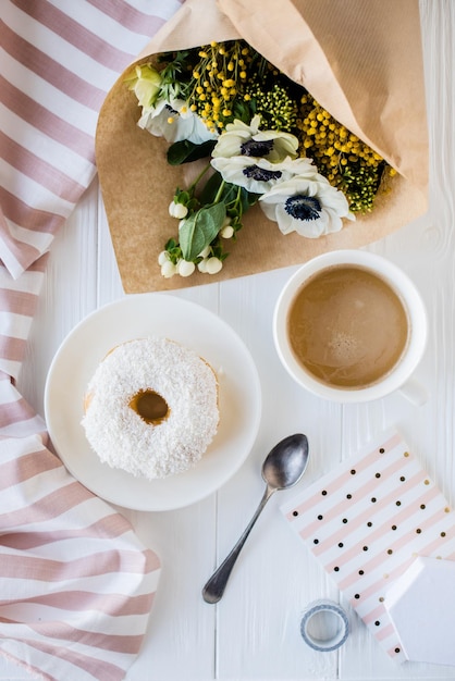 Coffe and a donut with fresh flowers