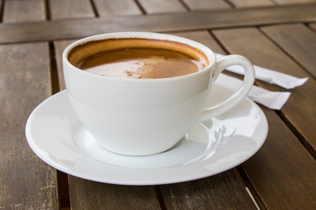 Coffee Americano in the white cup on the wooden table