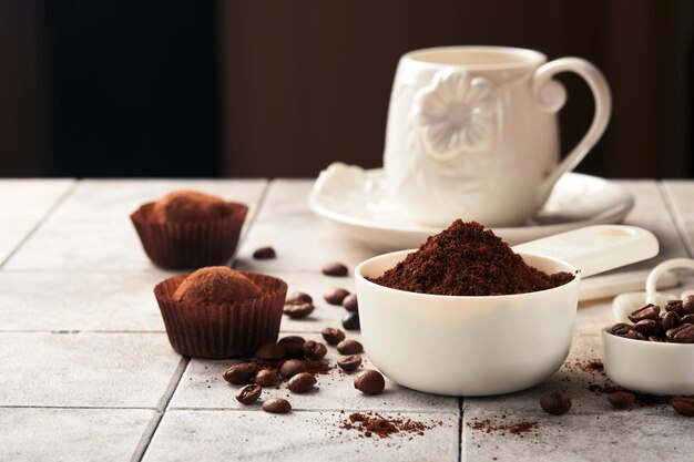 Coffee background Measuring spoons with ground coffee beans cup and sweet chocolate truffles on old tile cracked table background Food background Top view with space for your text