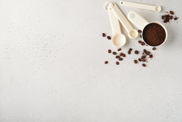 コーヒーの背景古いタイルに挽いたコーヒーと豆を入れた計量スプーンひびの入ったテーブルの背景コーヒーを作るための材料テキスト用のスペースのある上面図