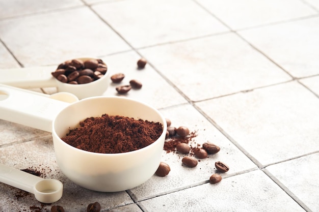 Coffee background Measuring spoons with ground coffee and beans on old tile cracked table background Ingredients for making coffee Top view with space for your text