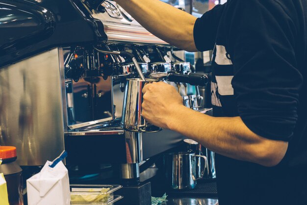 Coffee barista at work. Making cappuccino or latte on a coffee machine in an outdoor coffee shop.