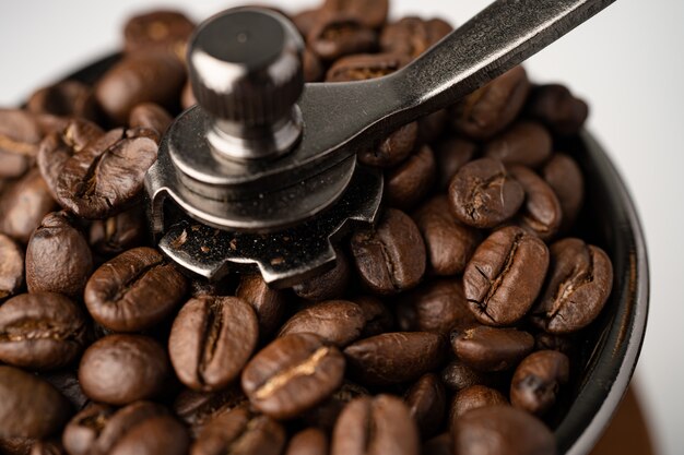 Coffee bean roasted in wooden grinder on white background.