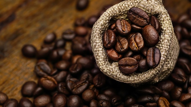 Coffee bean in sackcloth bag on wooden table