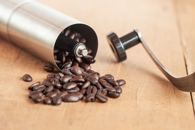 Coffee bean spill out of Coffee grinder on old wood.