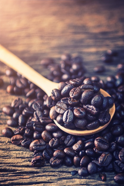 Coffee bean in spoon on wood background