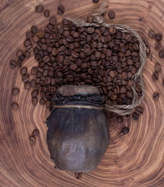 木製のテーブルの上の古代の木瓶のコーヒー豆