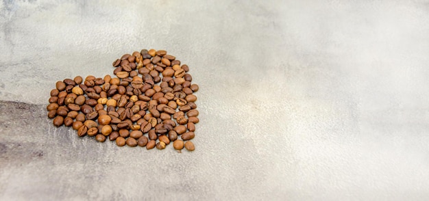 Coffee beans are laid out in shape of heart on gray concrete background space for text Top view