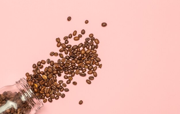 Coffee beans are scattered on a pink background. Coffee concept