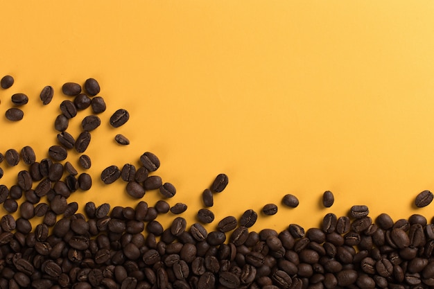 Photo coffee beans are scattered on a yellow paper  close-up, , commercial copyspace.