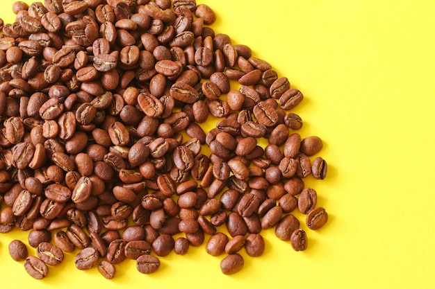 Фото Кофейные зерна как предпосылка изолированная на желтой предпосылке.