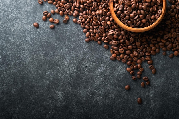 Coffee beans background roasted coffee beans on dark black\
stone background top view coffee concept mock up