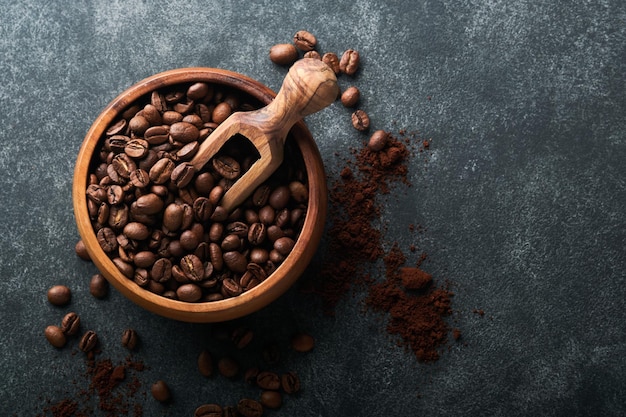 커피 콩 배경 짙은 검은색 돌 배경 위에 있는 나무 대나무 그릇에 볶은 커피 콩 상위 뷰 커피 개념 모의