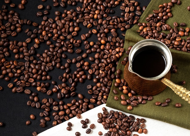 Coffee beans background. vintage cezve (turkish coffee) standing on coffee beans and linen napkin. Layout design with copy space