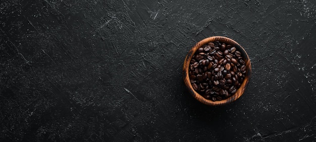 Coffee beans in a bowl On a black stone background Top view Free space for your text