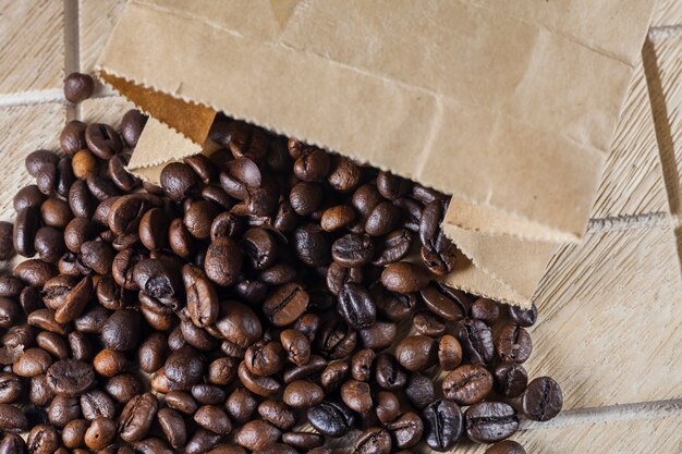 Coffee beans in a brown paper bag on wooden surface.