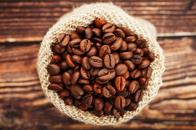 Coffee beans in a burlap bag on a wooden surface