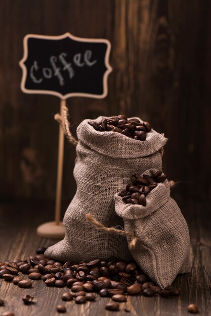 Coffee beans in burlap bags over wood