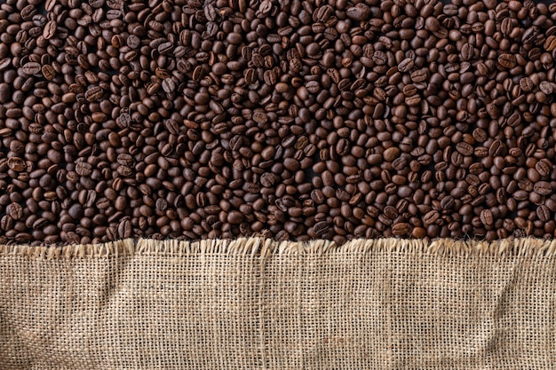 Coffee beans in burlap sack on old wooden background. top view