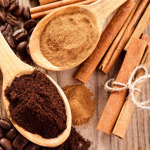 Coffee beans and cinnamon milled closeup in wooden spoons