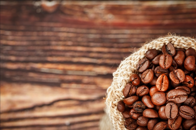 Coffee beans closeup in burlap bag on wooden surface