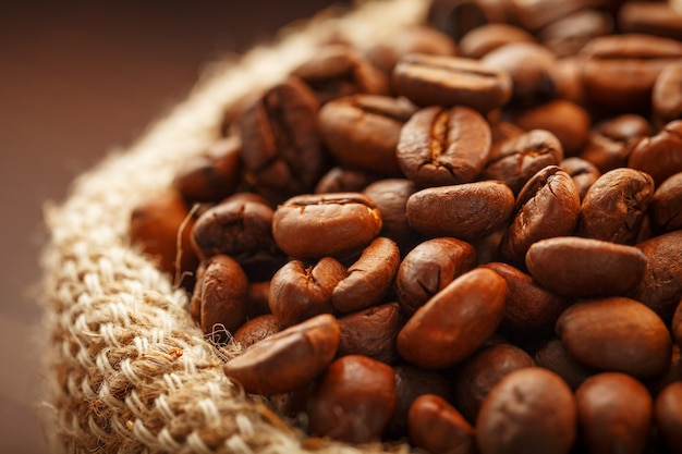 Coffee beans closeup in burlap bag on wooden surface