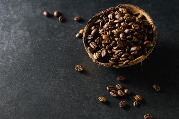 Coffee beans in coconut bowl on dark gray surface