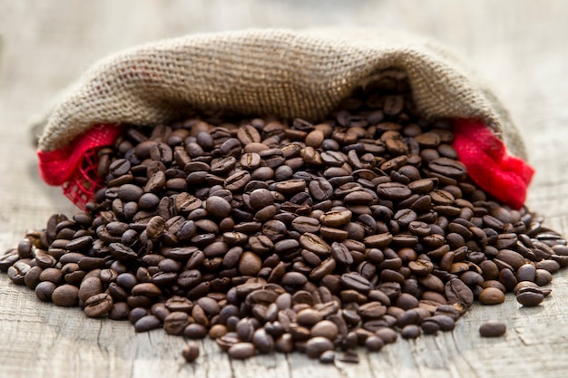 Coffee beans in coffee burlap bag on wooden surface