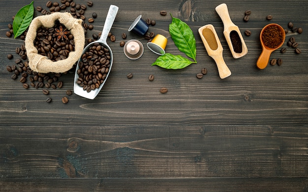 コーヒー豆のコーヒーカプセルと暗い木製のテーブルの上のコーヒーの粉。