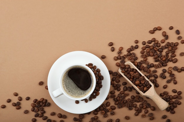 Кофейные зерна и чашка кофе на цветном фоне с местом для текста