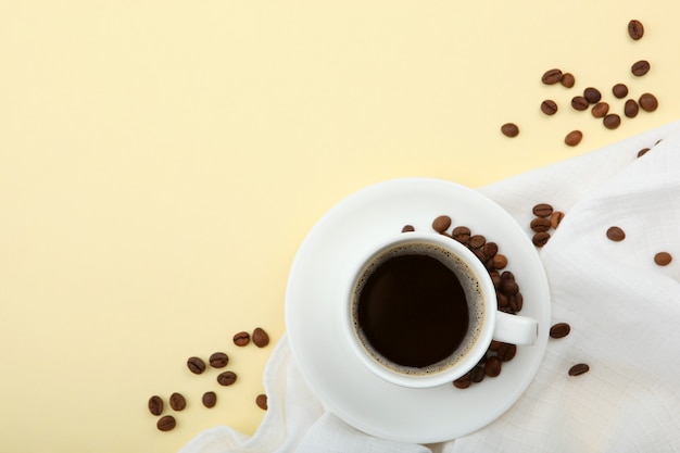 Coffee beans and coffee cup on colored background with place for text