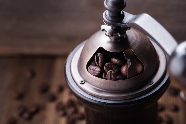 Coffee beans in coffee grinder on wooden surface