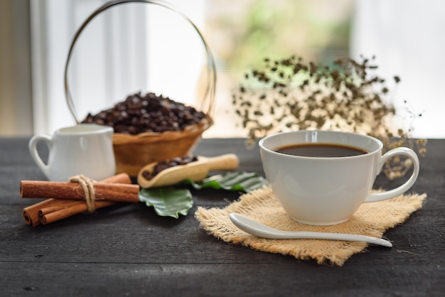 コーヒー豆と黒の牛乳入りコーヒー葉木製テーブル