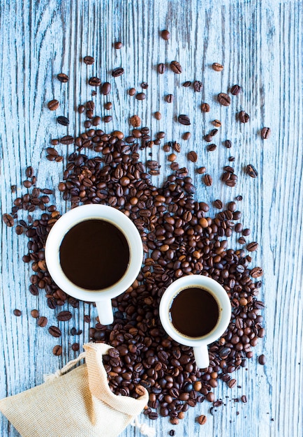 Кофейные зерна и чашка кофе с другими компонентами на различной деревянной поверхности. Свободное место для текста
