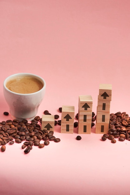 Coffee beans and cup with wooden blocks stacked in a growing shape with arrow as a coffee price increase concept