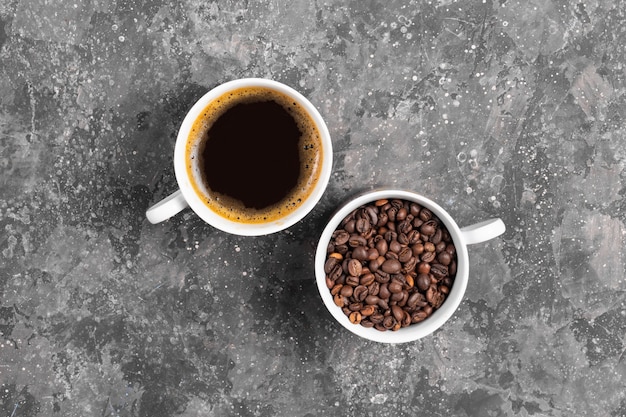 Coffee beans and espresso in white cups on gray background