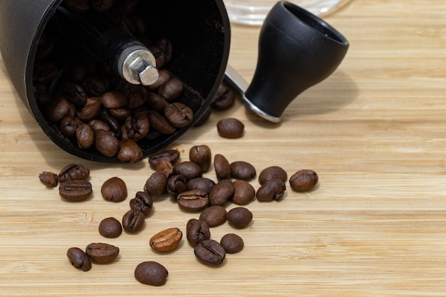 Фото Кофейные зерна упали с кофемолки на светлую древесину
