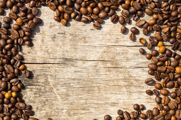 Coffee beans frame on grunge wooden background. Top view with copy space