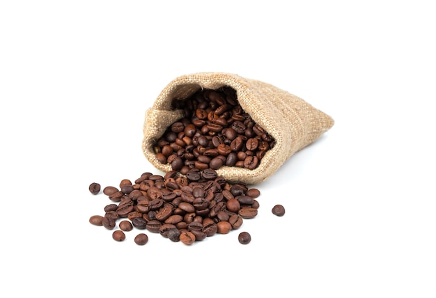 Coffee beans from a linen bag are spilled on the table on a white background.