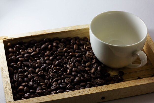 Coffee beans and glass are white on wood.