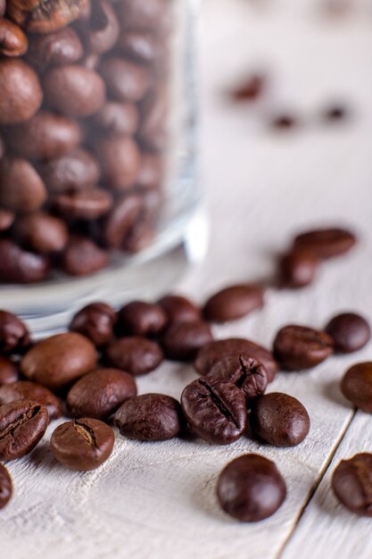 コーヒー豆または白い木製の表面に瓶に穀物