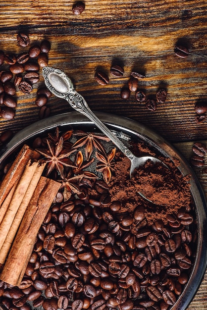 Coffee beans and ground coffee with spices on plate.