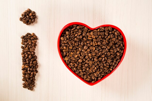 Coffee beans in heart bowl and exclamation mark made with coffee beans