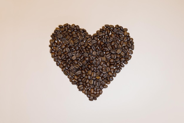 Coffee beans in heart shape on pink peach background
