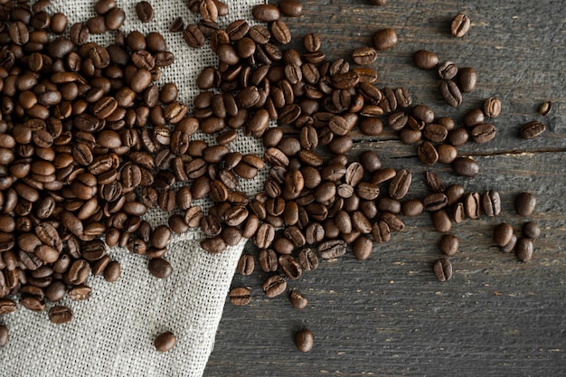 Coffee beans on a linen textile and on a wooden table background Fresh arabica coffee beans