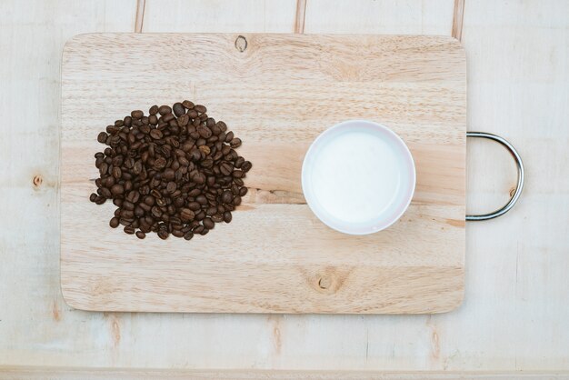 Coffee beans piled beside the coffee cups on the board.