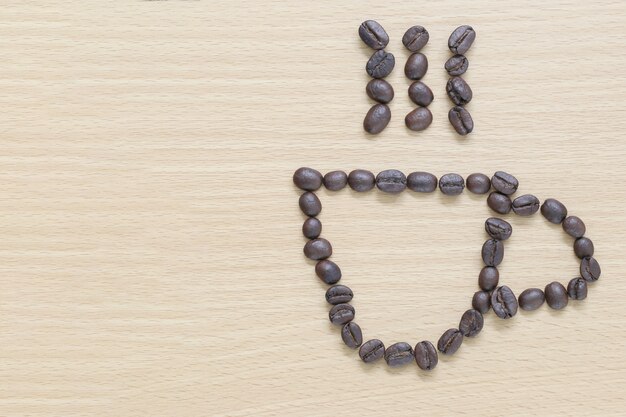 Coffee beans Placed in coffee cup shape on the wood background.