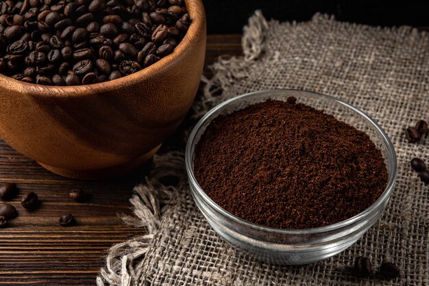 Coffee beans and powder on dark wooden background.