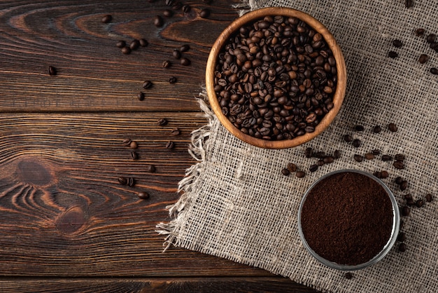 Coffee beans and powder on dark wooden background.